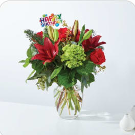 Red lilies and roses in a glass vase with a Happy Birthday pick