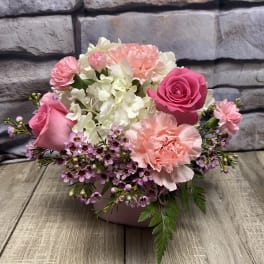 Pink and white floral arrangement in a low container