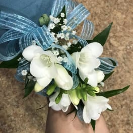White floral wrist corsage with blue ribbon and baby's breath
