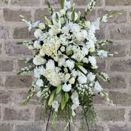 Large white funeral spray with lilies and roses on a stand