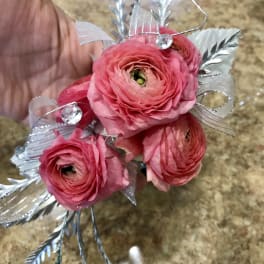 Small pink ranunculus bouquet with silver ribbon and decorative accents