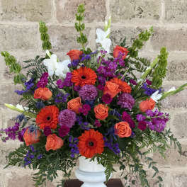 Bright mixed flower arrangement in a white vase with orange and purple blooms