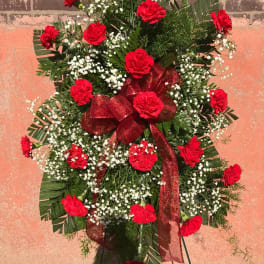 Standing spray of red carnations with white baby's breath and a red ribbon