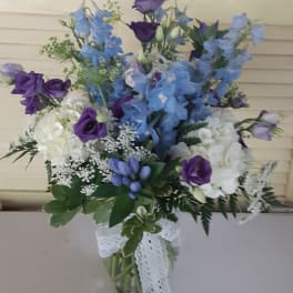 Blue and purple mixed bouquet in a glass vase with a lace ribbon