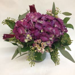 Purple hydrangea bouquet with greenery in a small vase
