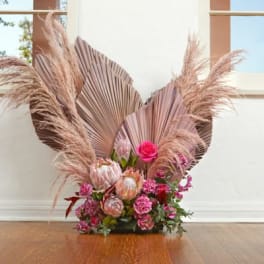 Pink floral arrangement with pampas grass and fan-shaped dried leaves