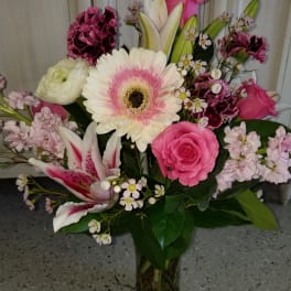 Mixed pink and white bouquet with roses, lilies, and gerbera daisies in a glass vase