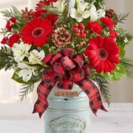 Red and white flower arrangement in a pale blue container with a plaid bow