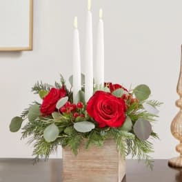 Red roses with three white taper candles in a wooden box
