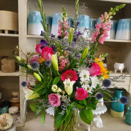Mixed bouquet in a clear glass vase with pink, white, yellow, and purple flowers