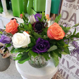 Bouquet of orange, white, and purple roses in a glass vase