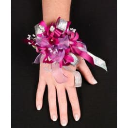 Pink wrist corsage with silver ribbon on a person's hand