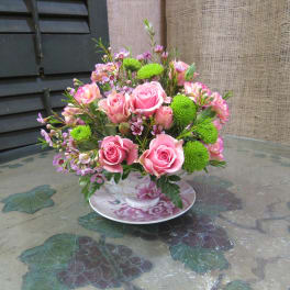 Pink rose bouquet in a floral teacup and saucer