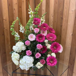 Tall arrangement of hot pink gerberas, pink roses, white hydrangeas, and green bells of Ireland.