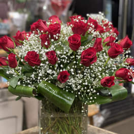 Red roses arranged in a clear glass vase with white baby's breath