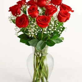 Red roses arranged in a clear glass vase with baby's breath