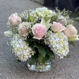 Pink roses and blue hydrangeas arranged in a glass vase