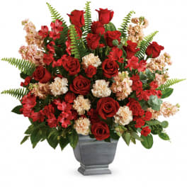 Red roses and peach carnations in a gray urn vase