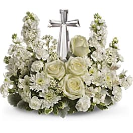 White floral arrangement with roses and stock around a silver cross