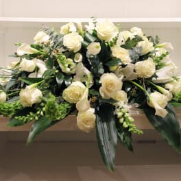 Low spray of white roses and calla lilies arranged in an elongated shape
