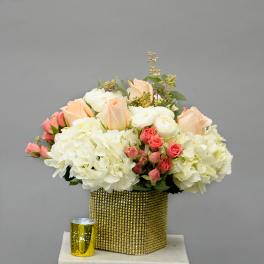 Bouquet of white and peach flowers in a gold square vase
