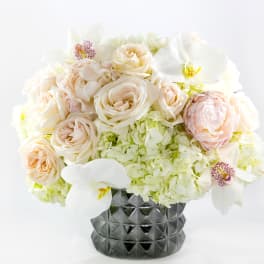 Cream and white floral arrangement in a dark textured vase
