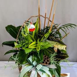 Basket arrangement of green plants with a fish decoration and striped ribbon