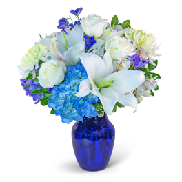White lilies, roses, hydrangea, and purple flowers in a blue vase