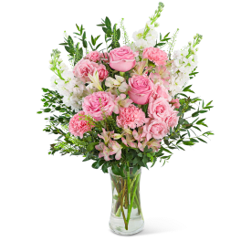 Pink roses and white flowers arranged in a clear glass vase