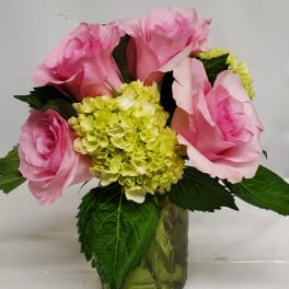 Pink roses and green hydrangea in a green glass vase