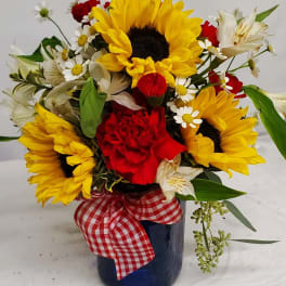 Sunflower and red carnation arrangement in a blue vase with a gingham ribbon