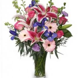 Mixed bouquet of pink lilies, roses, and gerbera daisies in a glass vase
