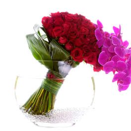 Red roses and pink orchids in a clear glass vase