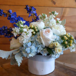 White and blue floral arrangement in a white container