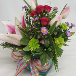 Pink tulips and red roses in a teal vase with a plaid ribbon