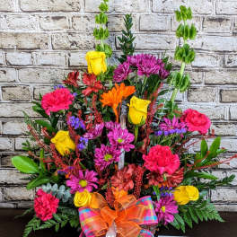 Colorful mixed flower arrangement with roses, carnations, and daisies in a basket