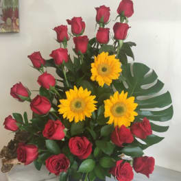 Red roses with yellow gerbera daisies in a black vase