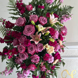 Large pink and magenta floral standing spray on a black easel