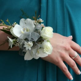 White floral wrist corsage with ribbon on a person's wrist