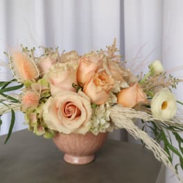 Peach roses and white ranunculus in a pink vase