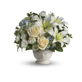 White lilies and cream roses arranged in a white vase