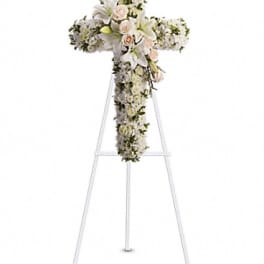 White floral cross arrangement on a stand with pale pink roses and lilies