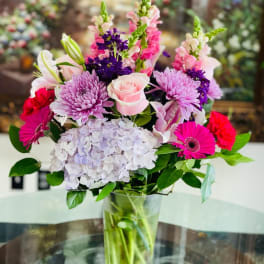 Mixed bouquet in a clear glass vase with pink, purple, and white flowers
