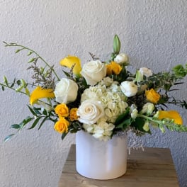 White and yellow floral arrangement in a white vase