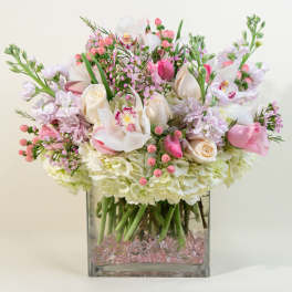 Pink and white floral arrangement in a square glass vase