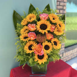 Sunflower and rose arrangement in a square glass vase