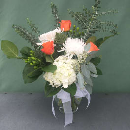 Bouquet of orange roses, white chrysanthemums, and white hydrangea in a glass vase