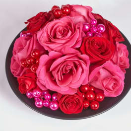 Round box of pink and red roses with shiny berry accents