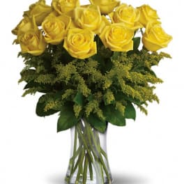 Yellow roses in a clear glass vase with green filler flowers