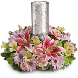 Pink lilies and pastel flowers arranged around a tall silver candle holder